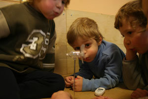drei kinder pusten in ein Miniaturwindrad
